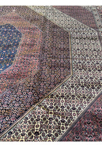 This handcrafted 12x17 Bijar Persian rug boasts an impressive central medallion that serves as the focal point, with symmetrical patterns extending outwards, encompassing a rich tapestry of symbolism and artistry