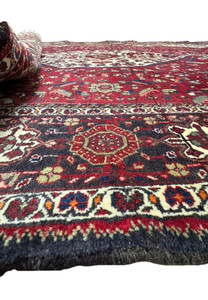 A side view of the Persian Qum Kork rug, with a portion rolled over to reveal the thickness and quality of the Kork wool weave.