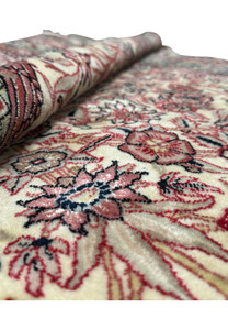 Image showing a folded section of the Persian Qum rug, illustrating the thickness and quality of the weave, with a glimpse of the detailed floral patterns and the soft sheen on the fabric.