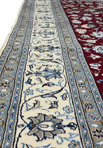 Detailed shot of the Persian Nain 9La rug's center, showing the complex interplay of floral designs and the plush texture of wool and silk