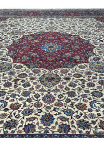 Full view of the central medallion of a Persian Mashad rug, displaying intricate floral and symmetrical patterns in rich red, blue, and gold, surrounded by detailed motifs and vibrant colors