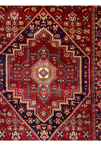 Detailed shot of the central medallion on a 3'4" x 5'1" Persian Gholtogh Rug. The medallion features intricate geometric and floral motifs in vibrant red, highlighted by navy blue and pastel accents. The craftsmanship and design reflect the rich tradition of Persian rug-making.