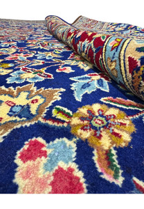 Detailed close-up of the central floral design on a Persian Kerman Rug, showcasing the vibrant reds, blues, and subtle earth tones in an intricate pattern