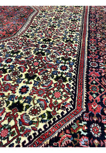 Pattern close-up of a Persian Bijar rug revealing dense knot structure, repeating Kurdish motifs, saturated reds, blues, and ivory tones with sharp definition.