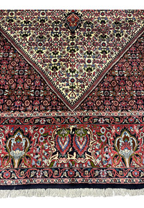 Lower border detail of a 9.8 x 12.2 Persian Bijar rug featuring bold floral motifs, deep red and navy accents, and tightly packed knots typical of Bijar weaving.