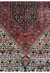 Field detail of a 9.8 x 12.2 Persian Bijar rug showing an ivory background filled with repeating floral and geometric motifs woven in red, blue, and green wool.