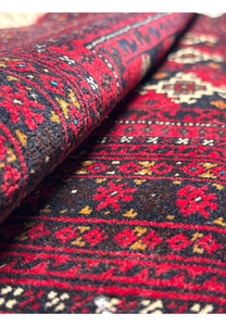 Rolled 3'6 x 4'9 Persian Baluch Rug showing intricate patterns up close.