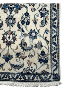 Close-up of the edge border of a Persian Nain Rug showcasing detailed floral motifs and fringes.