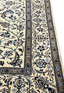 Angled side view of the 8'2 x 11'6 Persian Nain rug highlighting the floral patterns and silk details.