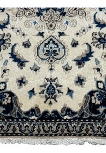 Detailed view of the lower portion of the Nain Persian rug, showing floral motifs and fine wool texture in ivory and navy.