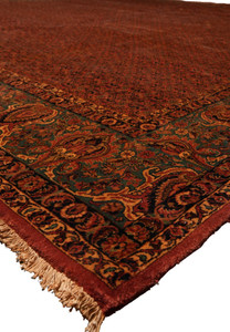 Corner detail of antique Bijar rug showing green floral border and fringe