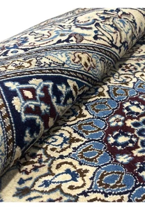 Rolled view of 6'7 x 6'7 Square Persian Nain Rug with silk highlights showing ivory field, navy floral border, and burgundy medallion details
