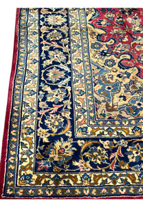 Lower edge of the 8'7 x 12'7 Distressed Persian Isfahan Rug showing intricate navy floral border, red fringe accents, and detailed Persian motifs in handwoven wool.