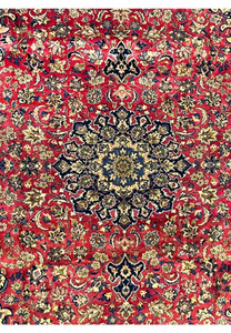 Close view of the central navy medallion surrounded by beige floral elements on a vibrant red background.