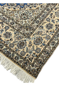Close-up of rug edge showing ivory border with intricate floral vines and beige outlines