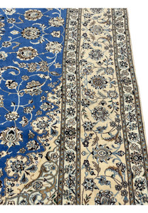 Side edge of hand-knotted Persian Nain rug showing wool and silk detail and royal blue field
