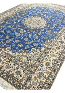 Angled view of Persian Nain 6 LA wool and silk rug showing royal blue field with ivory and beige floral motifs