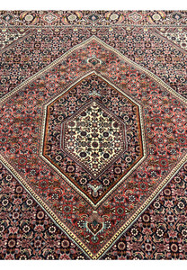 Detailed shot of the central medallion of Bijar Persian rug showing symmetrical floral motifs in ivory, rust, and navy with fine lattice outlines.