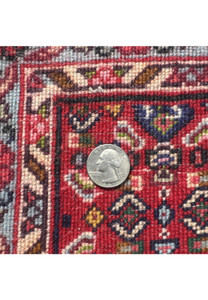 Macro of runner’s reverse with coin for scale, revealing tight knot count, red ground, navy, olive, and blue details.