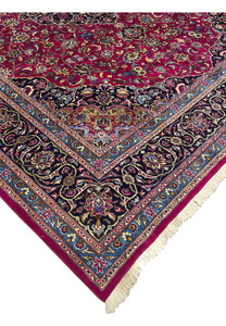 Edge view of Mashad rug showing fine weave, ruby border, and ivory fringe.
