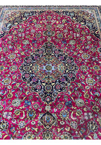 Close-up of medallion on Mashad rug featuring navy, ivory, and light blue floral layers.