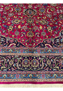 Lower border detail of Persian Mashad rug with navy field, sky blue guard border, and floral motifs.