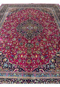 Top full view of Persian Mashad red wool rug showing floral medallion and navy borders.