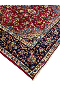 Edge of 8'5 x 11'8 Persian Isfahan rug showing fringe, navy border, and wool floral detailing.