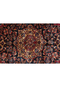 Medallion close-up of 1930s Persian Kashan rug with layered navy and ivory floral details surrounded by rich red field motifs.
