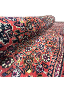 Rolled angle view highlighting the thick wool pile and detailed floral pattern of the Bijar Persian Iron Rug.