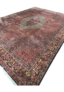 Angled low view of the 9'9 x 13'2 Bijar Persian Iron Rug showing the large cream medallion and brick red Herati field.
