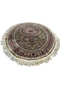 Oval Persian Qum pure silk rug laid flat, showing detailed floral medallion, fine knotting, and shimmering green, ivory, and burgundy tones.