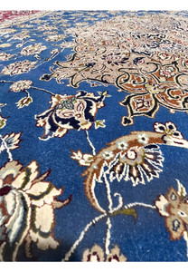 Color close-up capturing wool and silk texture with blue floral field, ivory accents, and fine detailing in the Persian Isfahan weave.
