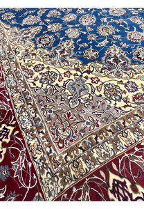 Inner border close-up revealing detailed beige, ivory, and floral motifs framing the blue field of the Isfahan rug.