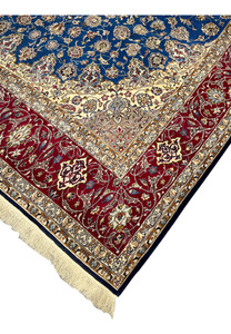 Edge and fringe view of the Persian Isfahan rug displaying precise knotting, red floral border, and navy outer edge.