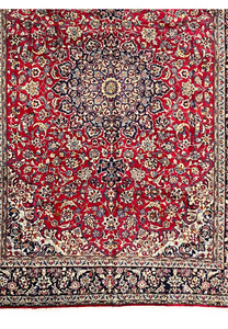 Lower section of Persian Isfahan rug displaying ruby red floral field and transition to navy border
