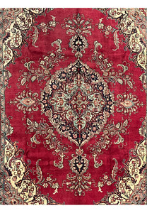 Midfield close-up of the vintage Tabriz rug showing patina, low pile, red background, and intricate floral vine details.