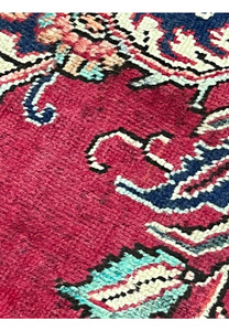 Closeup of patina wear on 10x13 vintage Persian Tabriz rug showing low-pile texture and softened red field with floral motifs.