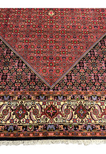 Lower border close-up of Persian Bijar rug showing thick wool pile, ivory floral scrollwork, navy outlines, and tightly packed construction