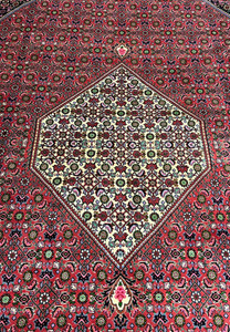 Central ivory diamond medallion on Persian Bijar iron rug filled with micro floral motifs over rich crimson and dark navy background