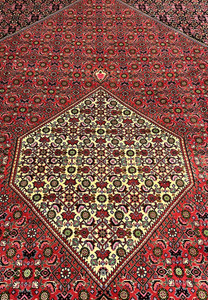 Field detail of Persian Bijar iron rug showing dense repeating Herati flowers in red, ivory, moss green, and soft sky blue
