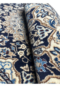 Rolled view of Persian Nain rug displaying dark navy pile, ivory border thickness, tight fine weaving, and soft texture