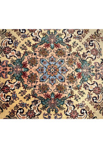 Close up of coral and slate blue central medallion with ivory and charcoal detailing on Persian Tabriz rug