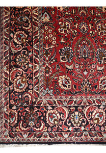 Close view of the all over floral midfield on a 6'6 x 9'6 Persian Bijar iron rug with brick red and navy tones