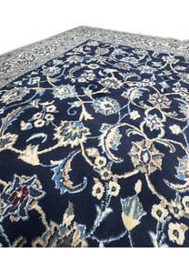 Detailed close-up of Persian Nain rug floral pattern with ivory blossoms, light blue vines, and precision knot structure