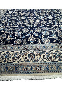 Lower border detail of Persian Nain rug featuring ivory floral cartouches with light blue and taupe color accents