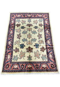 Top view of a Persian Farahan rug showing evenly spaced botanical leaf pattern on an ivory wool field