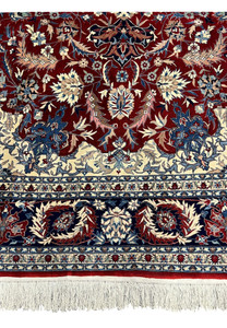 Lower border detail of Persian Isfahan rug showing navy floral guard borders, ivory accents, and hand knotted wool fringe