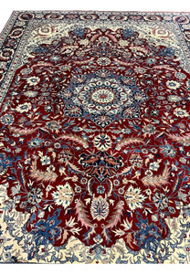 Top view of Persian Isfahan rug with symmetrical floral design, finely detailed medallion, and balanced red, ivory, and blue colors