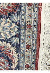 Backside of Persian Isfahan rug showing tight hand-knot structure, aligned wool foundation, detailed border pattern, and ivory fringe.